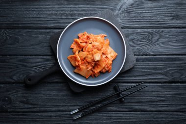 Siyah ahşap masada servis edilen Çin lahanalı nefis kimchi.