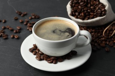 Gri masada bir fincan aromatik kahve ve fasulye.