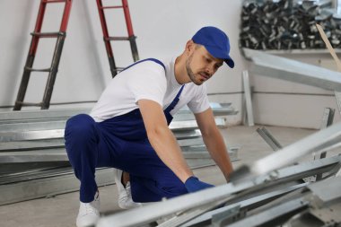 Construction worker with used building materials in room prepared for renovation