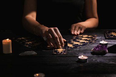 Kahin, karanlıkta tarot kartlarıyla geleceği tahmin ediyor. Yakın plan.