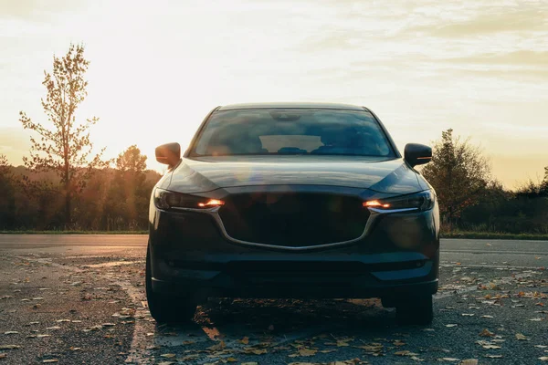 Stock image Black modern car parked on road at sunset