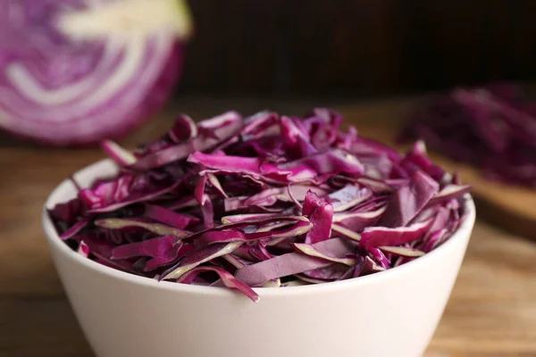 Fresh chopped red cabbage in bowl on wooden table, closeup