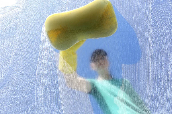 Woman cleaning glass with sponge on sunny day