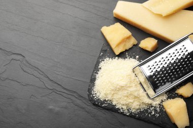 Tam ve rendelenmiş parmesan peyniri siyah masada, düz yerde. Metin için boşluk