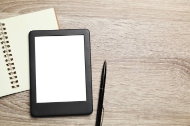 Defter ve kalemle tahta masaya dizilmiş e-kitap okuyucusu. Metin için boşluk