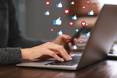 Dizüstü bilgisayar ve akıllı telefon kullanan genç bir kadın, yakın plan. Sosyal medya