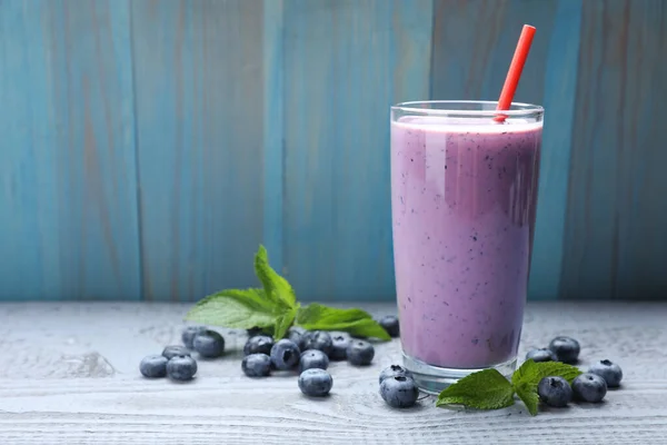 Stock image Glass of freshly made blueberry smoothie on grey wooden table. Space for text