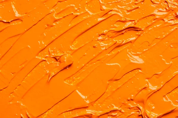 Beautiful strokes of orange oil paint as background, closeup