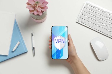 Akıllı telefonu olan kadın beyaz masada VPN 'i açtı.