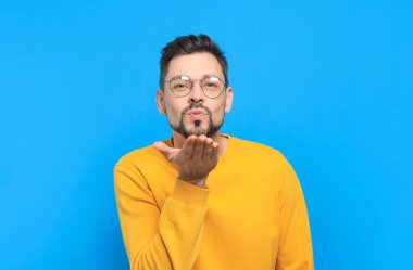 Açık mavi arka planda öpüşen yakışıklı adam.