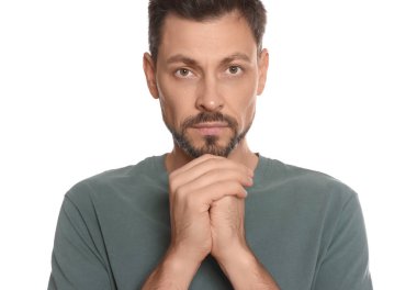 Ellerini kenetleyip beyaz arka planda dua eden adam.