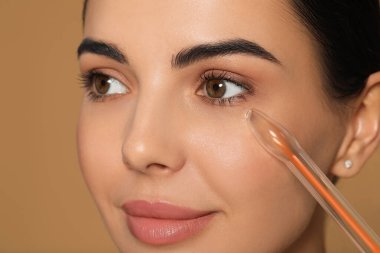 Bej arka planda yüksek frekanslı darsonval aygıt kullanan kadın, yakın plan