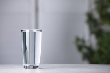 Açık gri masa üzerinde bir bardak saf su, metin için boşluk.
