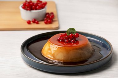 Kırmızı üzümlü karamelli puding ve beyaz ahşap masada nane.
