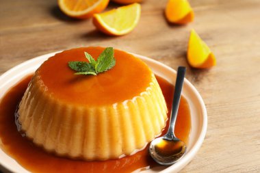 Karamelli lezzetli puding ve ahşap masada nane, yakın plan.