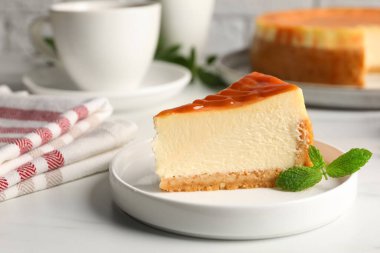 Piece of delicious caramel cheesecake served on white marble table, closeup