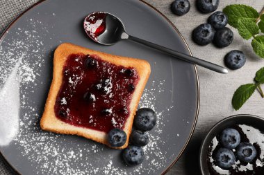 Gri ahşap masada reçelli ve yaban mersinli lezzetli tost.