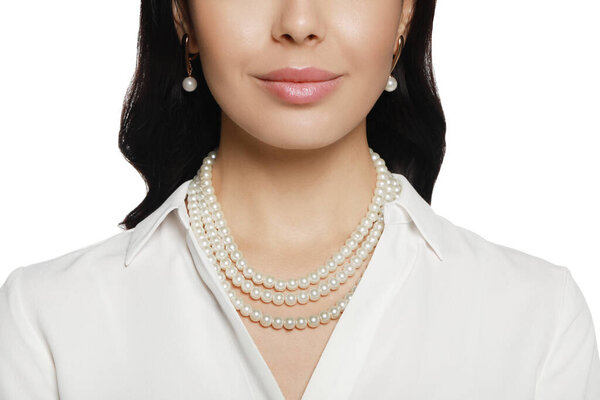 Молодая женщина носит элегантные жемчужные украшения на белом фоне, крупным планом