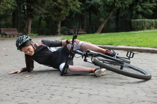 在公园里从自行车上掉下来的年轻女子 — 图库照片