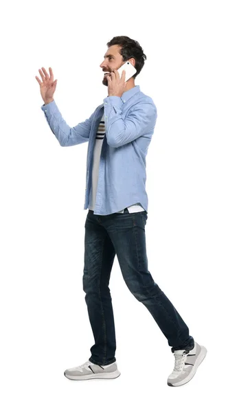 Bonito Homem Falando Smartphone Enquanto Caminha Contra Fundo Branco — Fotografia de Stock
