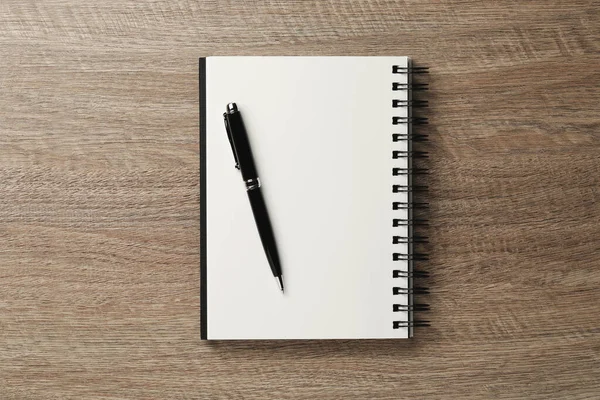 stock image Notebook and pen on wooden table, top view