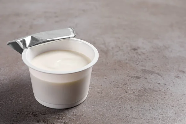 stock image Plastic cup with delicious organic yogurt on grey table, closeup. Space for text