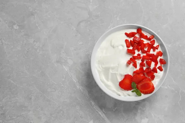 stock image Delicious yogurt served with strawberries on grey marble table, top view. Space for text