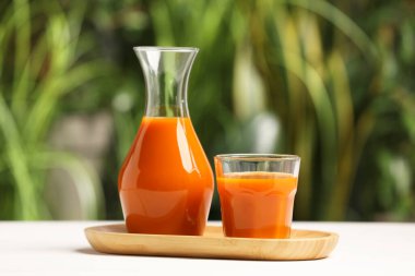 Dışarıdaki beyaz masada havuç suyu, yakın plan.