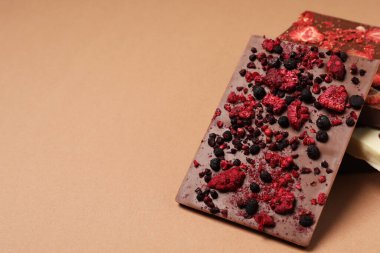 Bej arka planda dondurulmuş meyveleri olan farklı çikolatalar, metin için boşluk