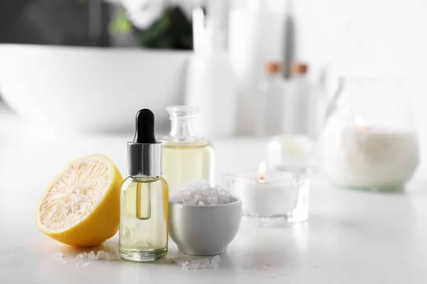 stock image Essential oils, sea salt and lemon on white table in bathroom, closeup. Space for text