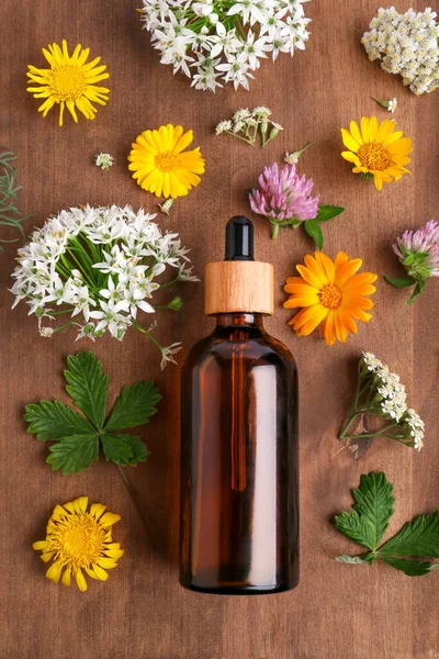 Fles Etherische Olie Verschillende Wilde Bloemen Houten Tafel Plat Gelegd — Stockfoto