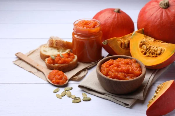 stock image Delicious pumpkin jam and fresh pumpkins on white wooden table