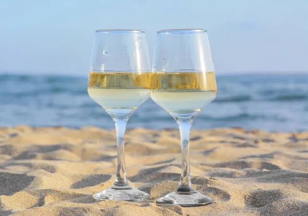 stock image Glasses of tasty wine on sand near sea