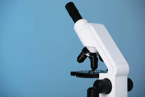 Modern microscope on blue background. Space for text