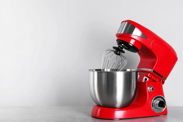 Modern red stand mixer on light gray table, space for text