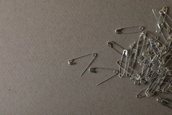 stock image Pile of safety pins on grey textured background, flat lay. Space for text