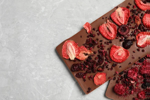Chocolate bars with freeze dried berries on grey marble table, closeup. Space for text