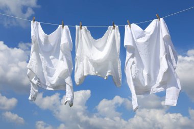 Temiz giysiler gökyüzüne karşı çamaşır ipine asılı. Çamaşır kurutuyorum.