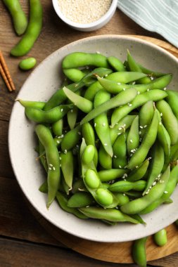 Green edamame beans in pods served with sesame seeds on wooden table, flat lay clipart