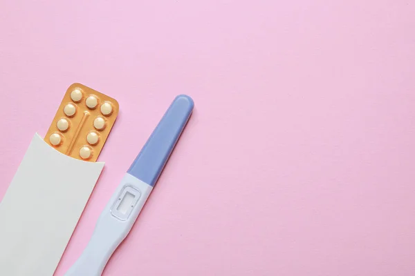 Birth control pills and pregnancy test on pink background, top view. Space for text