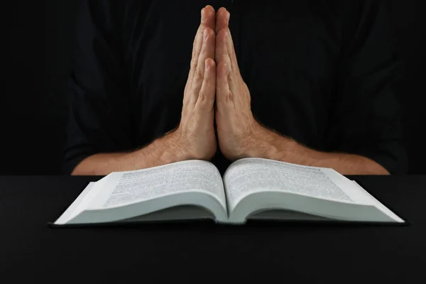 聖書のある人は黒のテーブルで祈ります — ストック写真