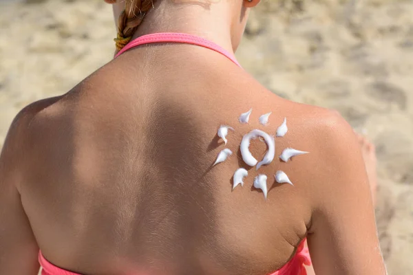 Little girl with sun protection cream on back outdoors, closeup