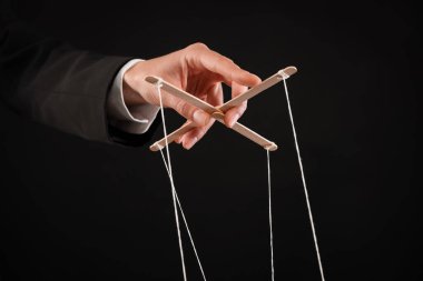 Siyah arka planda kukla iplerini çeken kadın, yakın plan.