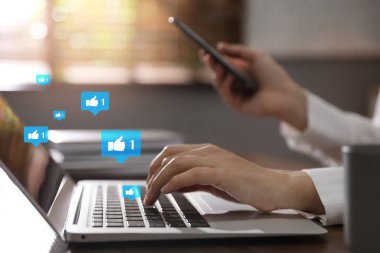 Dizüstü bilgisayar ve akıllı telefon kullanan genç bir kadın, yakın plan. Sosyal medya