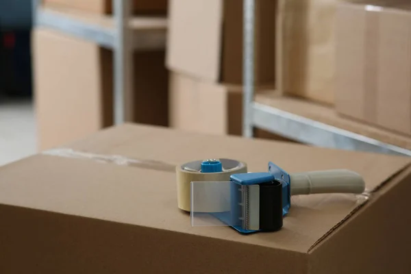 Adhesive tape dispenser on cardboard box indoors