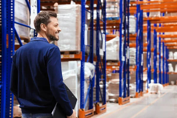 stock image Happy manager holding clipboard in warehouse with lots of products. Space for text