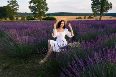 Beautiful young woman sitting in lavender field