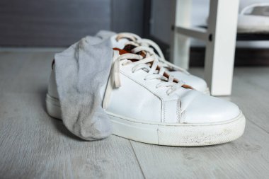 Beyaz ahşap zeminde kirli çorapları olan spor ayakkabıları.