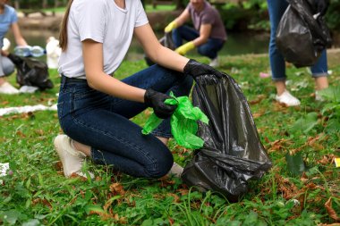 Plastik çantalı kadın parkta çöp topluyor, yakın plan.