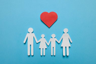 Kağıt aile figürleri ve açık mavi arka planda kırmızı kalp düz yatıyordu. Sigorta konsepti